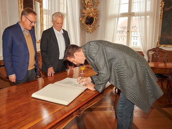 Casey Jacobson trägt sich ins Goldene Sportbuch der Stadt Bamberg ein, neben OB Andreas Starke und Norbert Sieben